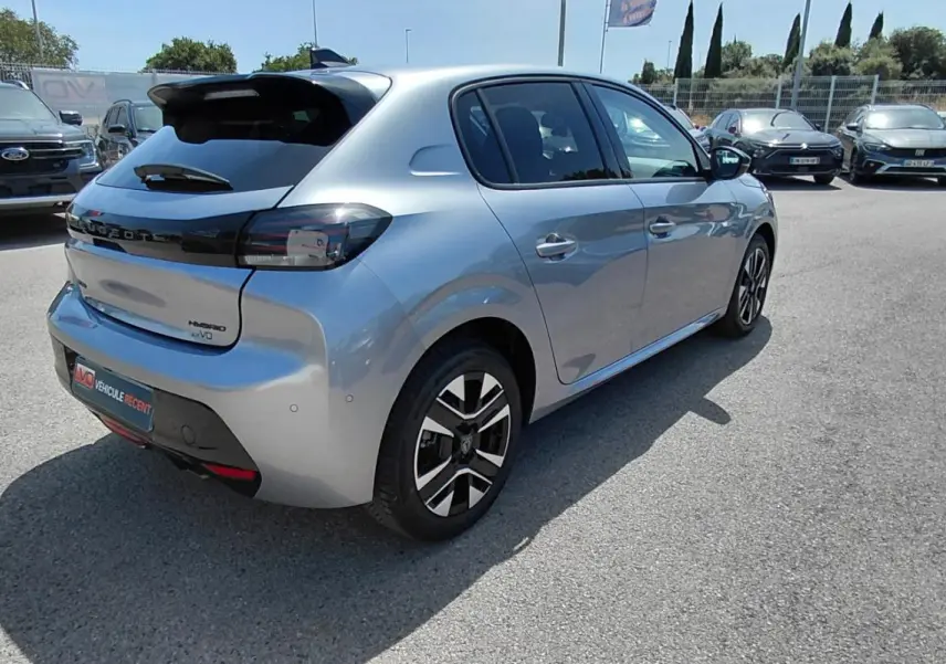 Vue 3/4 arrière droit d'une Peugeot 208 Hybrid gris métallisé avec jantes alliage et feux arrière fumés.