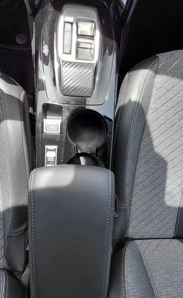 Vue plongeante sur la console centrale noire et les sièges gris du Peugeot 208 Hybrid 110 ch e-DCS6 Allure 2025.
