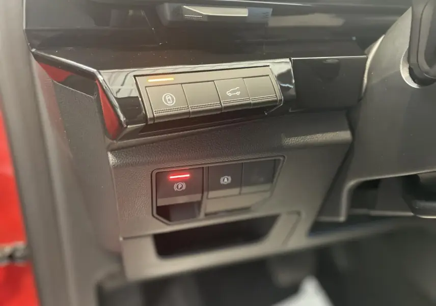 Gros plan sur les commandes du tableau de bord côté gauche d'une Renault Rafale rouge, avec bouton frein de parking activé.