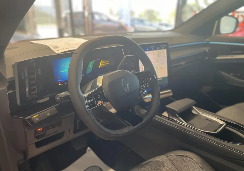 Intérieur Renault Rafale 2025 vu côté conducteur, volant compact avec logo Renault et écran tactile central lumineux.