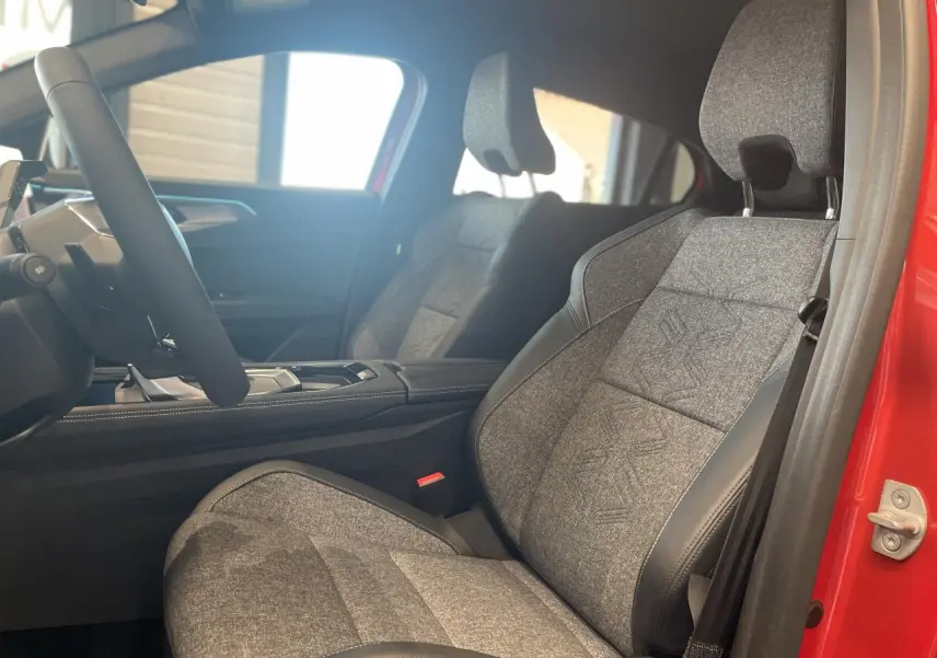 Intérieur côté conducteur du Renault Rafale 2025, siège sport gris textile avec surpiqûres, porte rouge visible.