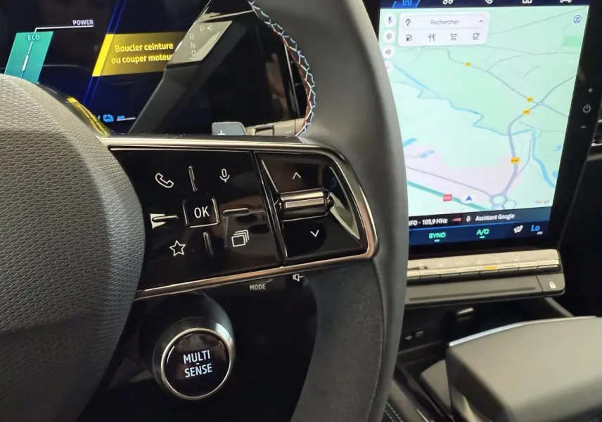 Gros plan sur le volant cuir et suede avec commandes multifonctions du Renault Espace esprit Alpine 2025, écran tactile de navigation visible.
