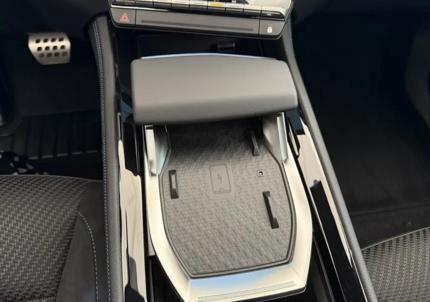 Vue rapprochée de la console centrale noire du Renault Espace 2025 avec zone de recharge sans fil et accoudoir gris.