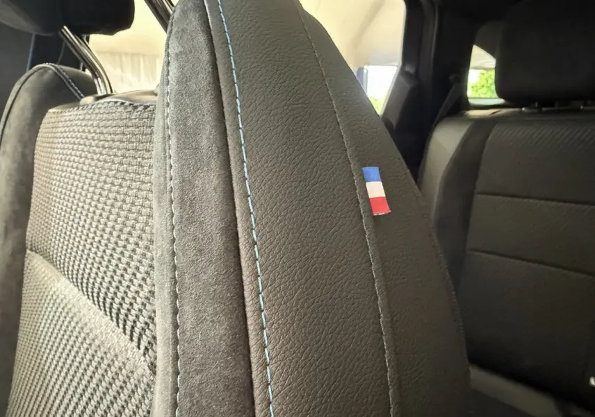 Gros plan sur l’appui-tête avant en cuir noir avec surpiqûres bleues et drapeau tricolore dans l’habitacle du Renault Espace 2025.