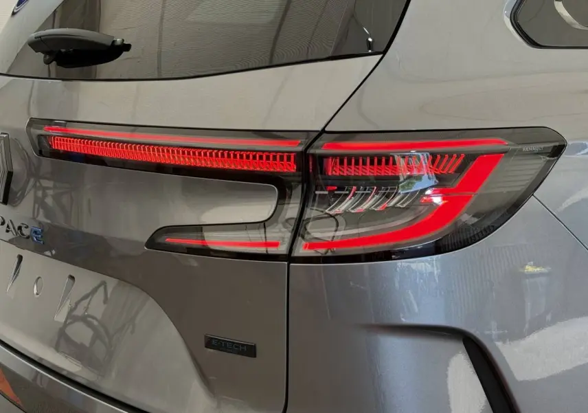 Gros plan sur le feu arrière droit rouge d'un Renault Espace gris foncé hybride E-Tech 2025, avec logo visible.