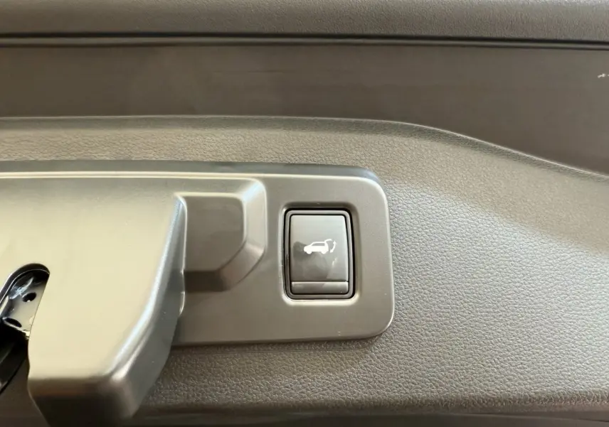 Gros plan sur le bouton d'ouverture électrique du coffre dans un Renault Espace gris foncé esprit Alpine 2025.