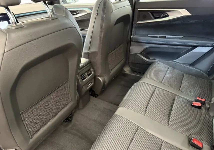 Vue intérieure arrière côté droit du Renault Espace gris foncé, sièges en tissu et cuir noir avec ceintures rouges.