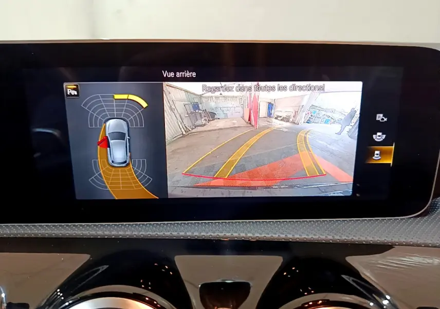 Écran tactile intérieur montrant la caméra de recul et l'aide au stationnement d'une Mercedes Classe A 180 AMG Line noire.