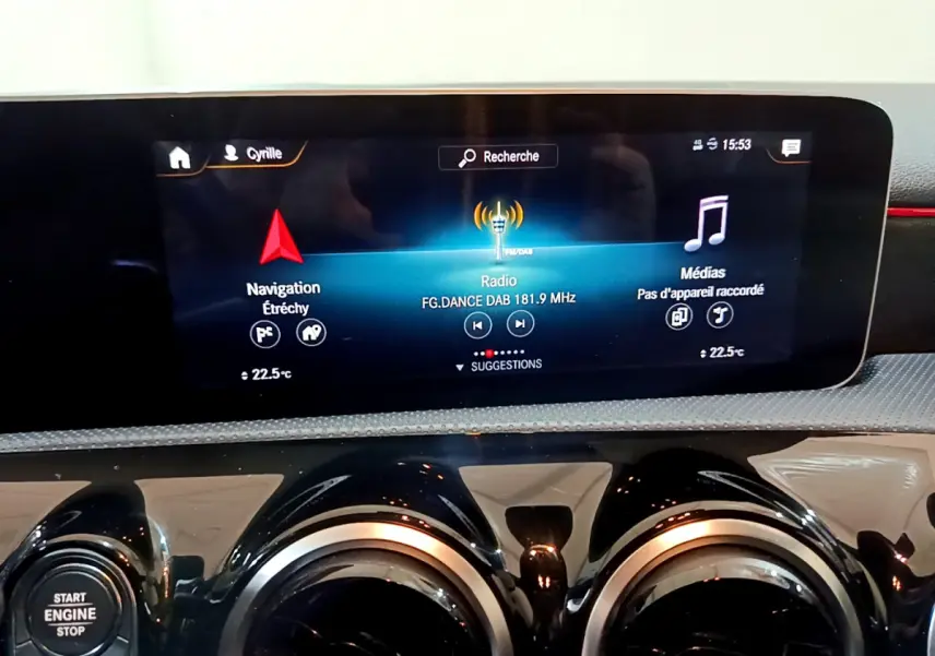 Écran tactile central affichant navigation et radio, avec commandes d’aération rondes dans l’habitacle d’une Mercedes Classe A noire.