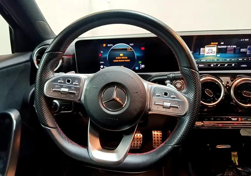 Volant cuir perforé avec commandes multifonctions et tableau de bord numérique d'une Mercedes Classe A 180 AMG Line 2019.