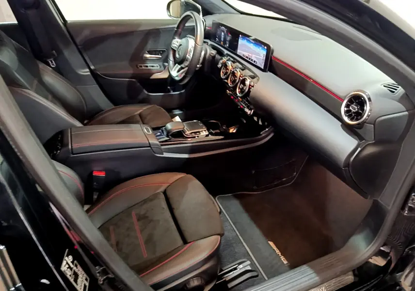 Intérieur noir de la Mercedes Classe A 180 AMG Line 2019, vue côté passager avec tableau de bord et sièges sport rouges.
