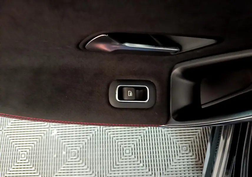 Gros plan sur la poignée intérieure et bouton de la portière côté gauche d’une Mercedes Classe A 180 AMG Line noire.