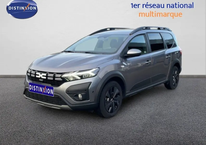 Vue 3/4 avant droit d'un Dacia Jogger gris schiste métal avec toit noir et jantes noires sur sol gris.