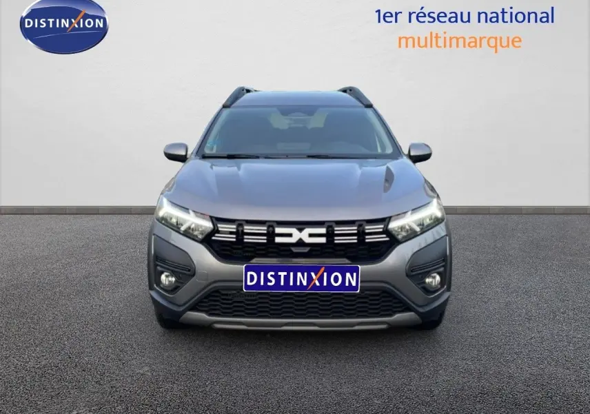 Vue de face du Dacia Jogger gris schiste métal 2025 avec calandre noire et feux LED allumés.