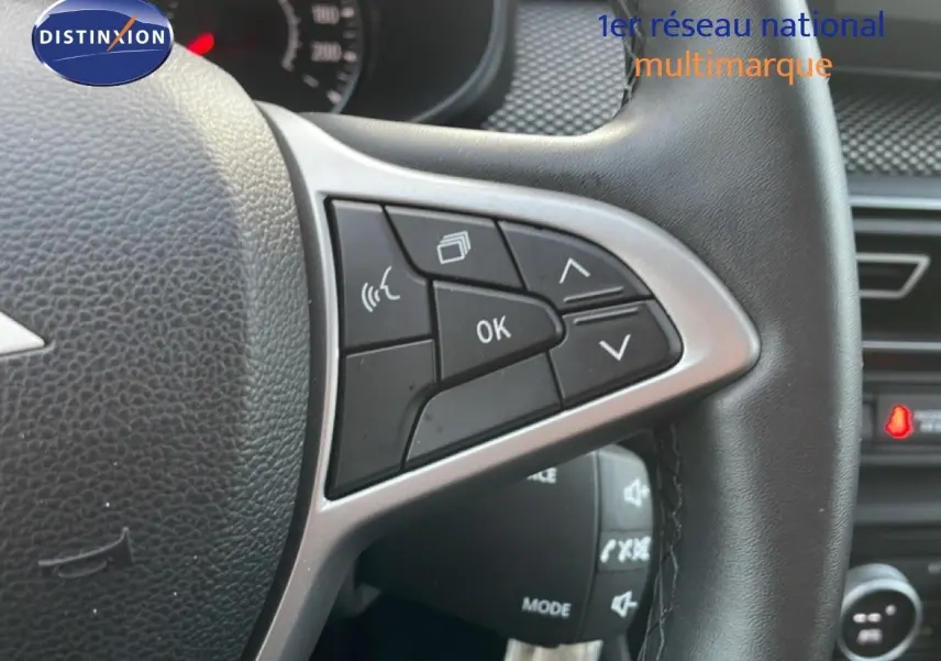 Gros plan sur les commandes au volant en cuir noir du Dacia Jogger gris schiste, avec tableau de bord en arrière-plan flou.