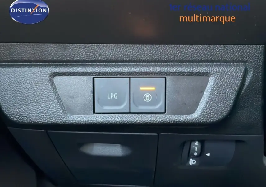 Gros plan sur les boutons de commande LPG et verrouillage intérieur du tableau de bord d’un Dacia Jogger gris schiste métal.