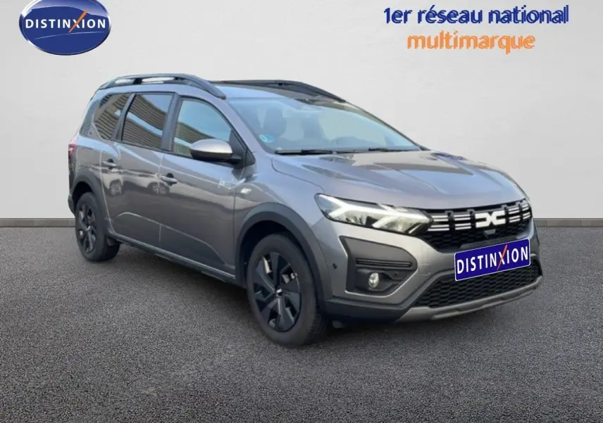 Dacia Jogger gris schiste métal en 3/4 avant droit, avec toit noir et jantes foncées sur fond neutre.