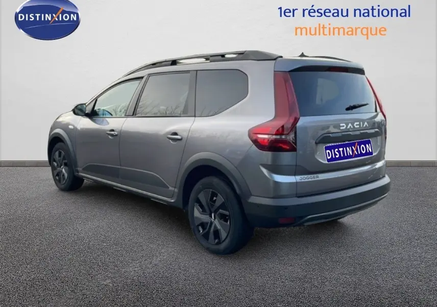 Vue 3/4 arrière droite d'un Dacia Jogger gris schiste métal avec barres de toit et vitres teintées.