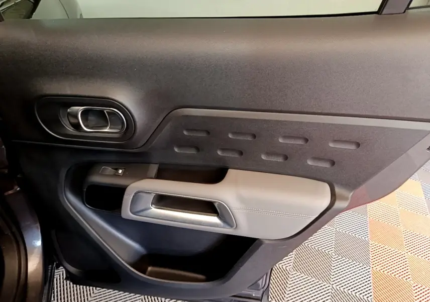 Vue intérieure de la porte avant gauche du Citroën C5 Aircross gris foncé, avec poignée argentée et garniture noire.