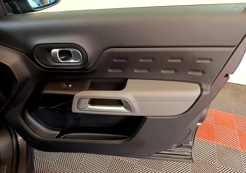 Vue intérieure du panneau de porte avant gauche du Citroën C5 Aircross 2020, avec accoudoir gris clair et poignée argentée.