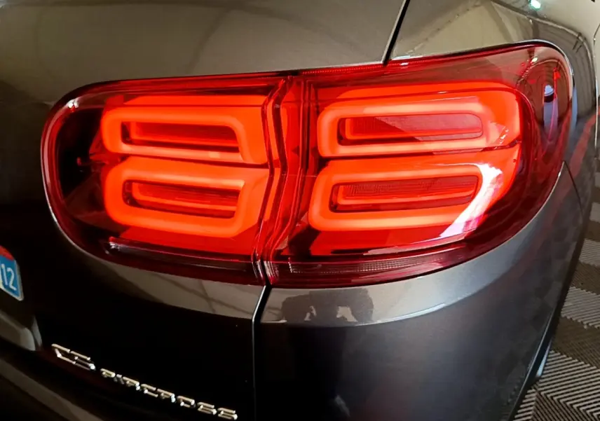 Gros plan sur le feu arrière droit rouge vif d’un Citroën C5 Aircross gris foncé, avec logo et partie de la plaque visible.