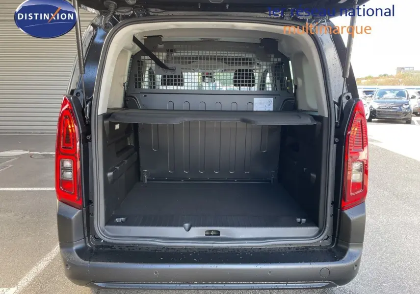Coffre ouvert en vue arrière d'un Citroën Berlingo noir Perla Nera, montrant l'espace de chargement et la grille de séparation.