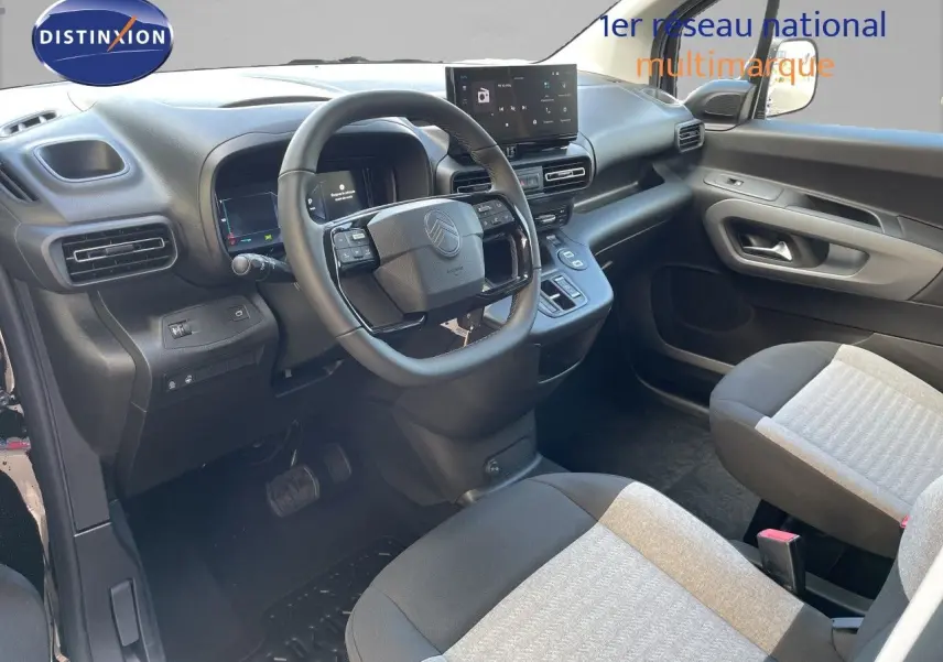 Vue intérieure côté conducteur du Citroën Berlingo 2026, tableau de bord noir avec écran tactile et sièges tissu bicolore.