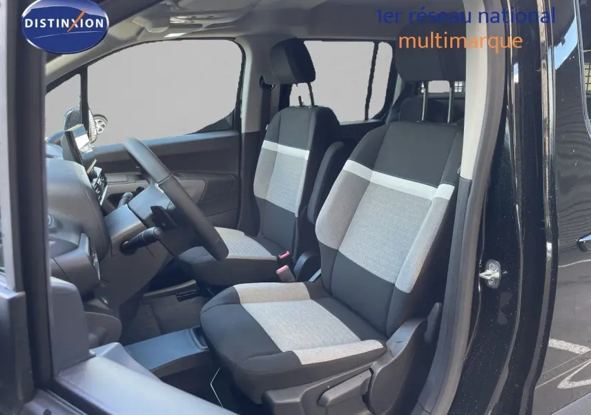 Vue intérieure côté conducteur du Citroën Berlingo noir Perla Nera, sièges tissu bicolore gris et noir visibles.