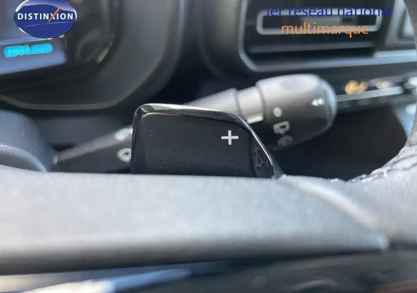 Gros plan sur la palette de changement de vitesse "+" du volant d'un Citroën Berlingo noir Perla Nera, intérieur sombre.