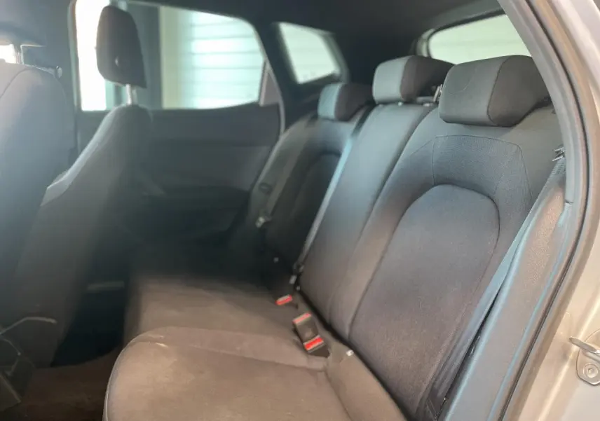Vue intérieure côté droit montrant la banquette arrière noire textile du SEAT Arona 2024 avec appuie-têtes et ceintures de sécurité.
