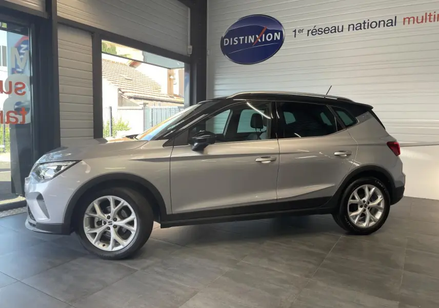Vue latérale droite du SEAT Arona 2024 gris GRS avec jantes alliage 16 pouces dans un showroom.