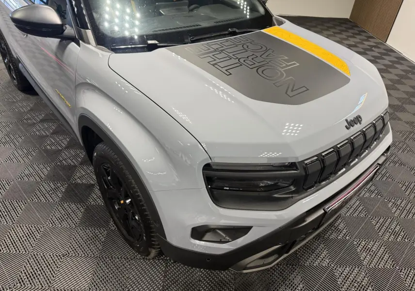 Vue 3/4 avant gauche du Jeep Avenger gris avec capot noir mat marqué The North Face et jantes noires.