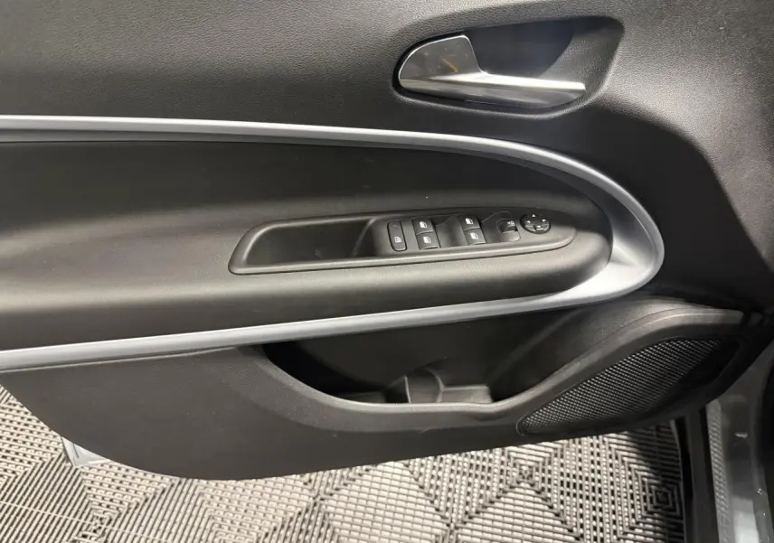 Vue intérieure du panneau de porte avant gauche gris foncé avec commandes électriques et poignée chromée du Jeep Avenger Hybrid 2026.