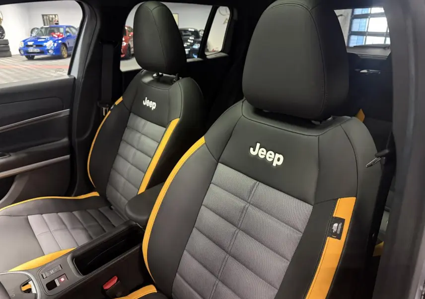Vue intérieure sur les sièges avant gris et noir avec surpiqûres jaunes et logo Jeep brodé sur appuie-têtes.