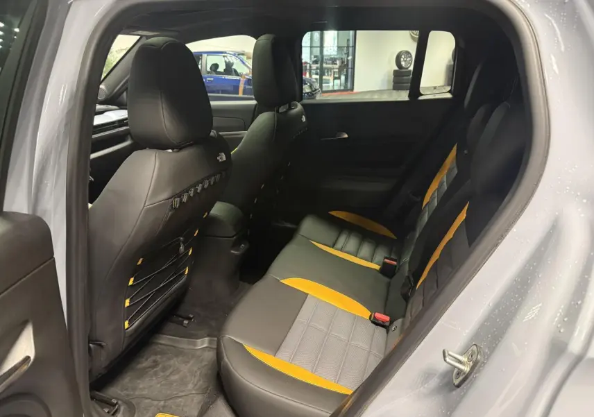 Vue intérieure côté gauche montrant la banquette arrière bicolore noire et jaune du Jeep Avenger Hybrid 4xe gris avec logo The North Face.