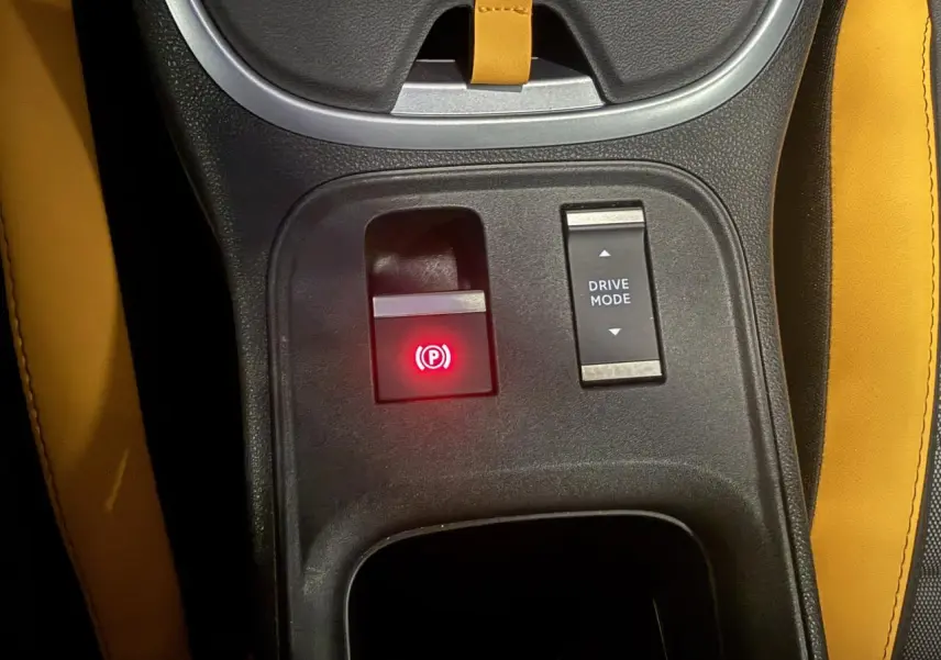 Vue rapprochée du frein de stationnement électrique et bouton Drive Mode sur la console centrale avec sellerie jaune du Jeep Avenger Hybrid 4xe.