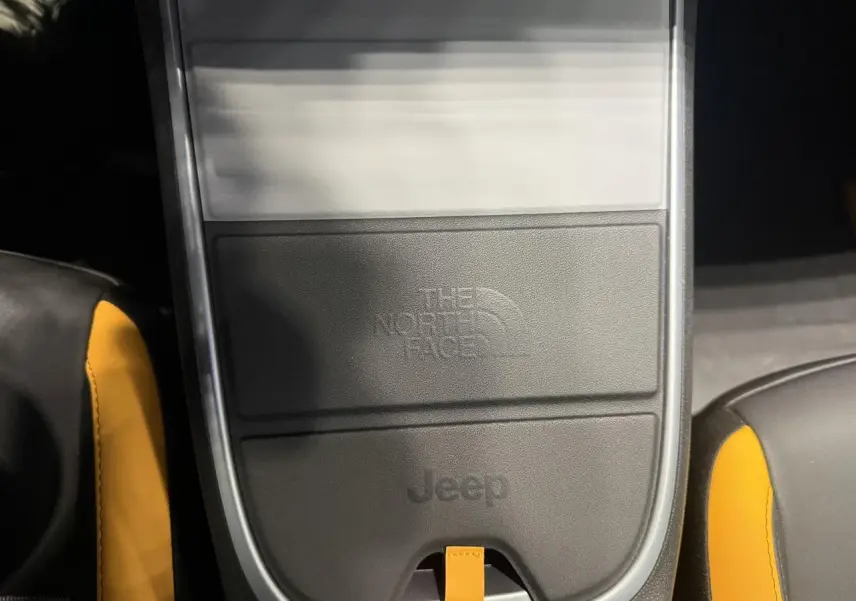 Gros plan sur la console centrale noire avec logo The North Face et Jeep, sellerie noire et jaune visible.