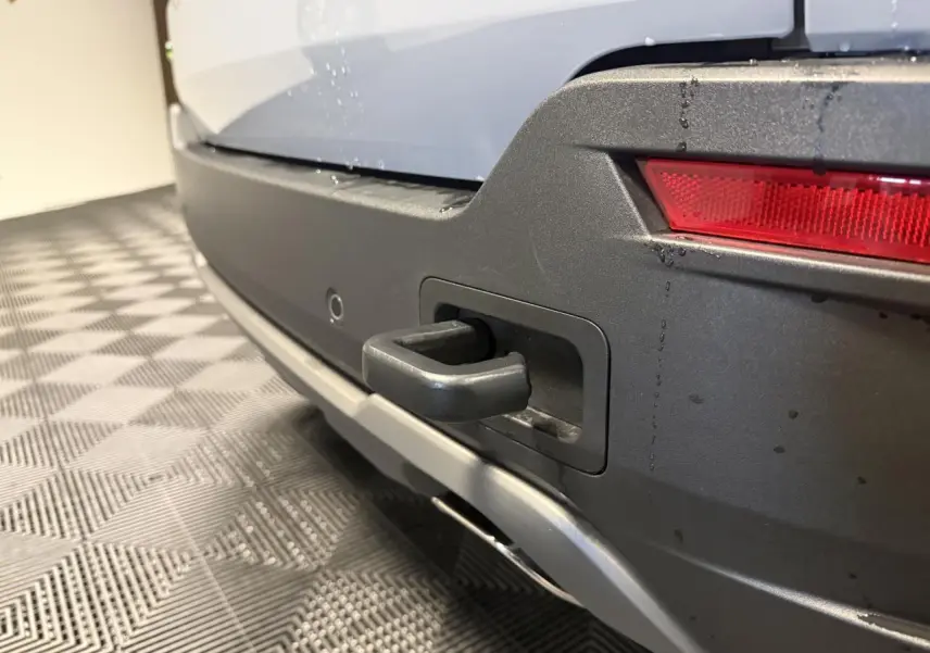 Gros plan sur le crochet de remorquage arrière du Jeep Avenger gris avec pare-chocs noir et feu arrière LED.