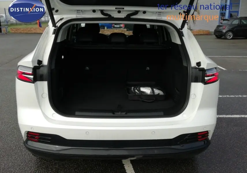 Vue arrière d'un MG MOTOR EHS 1.5T PHEV 272CH Luxury blanc nacré avec coffre ouvert et intérieur noir visible.