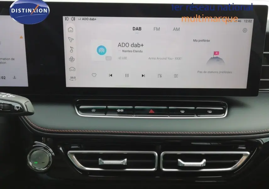 Vue rapprochée de l’écran tactile et de la console centrale noire du MG MOTOR EHS blanc perle, affichant la radio DAB.