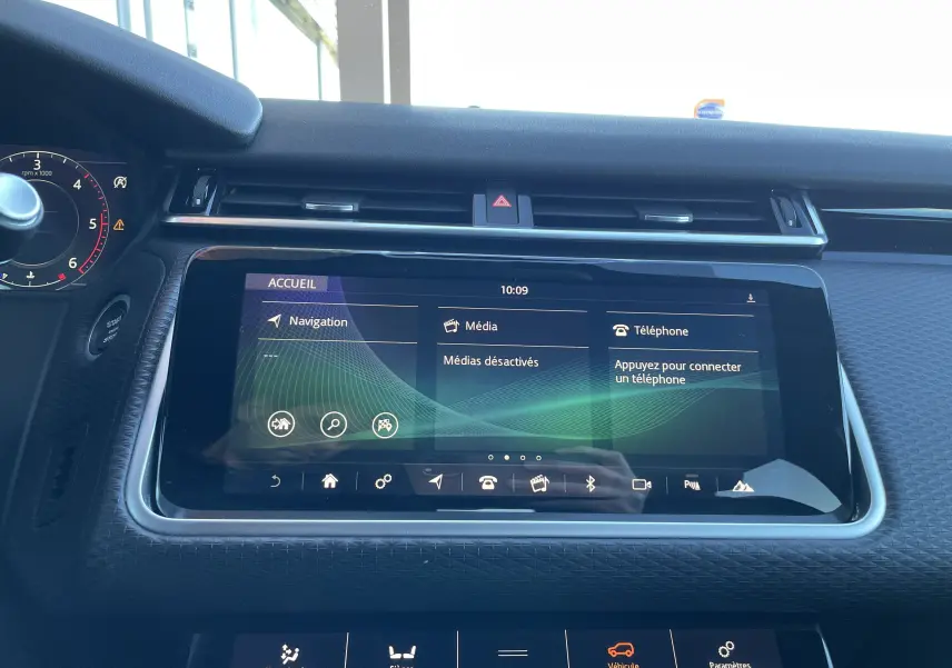 Vue rapprochée de l'écran tactile central et du tableau de bord noir du Range Rover Velar gris Corris, affichant le menu multimédia.