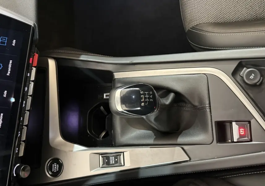 Vue plongeante sur la console centrale de la Peugeot 308 bleu, mettant en valeur le levier de vitesse manuel et le bouton start/stop.
