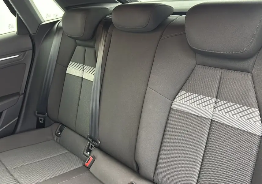Vue intérieure des sièges arrière de l'Audi A3 Sportback 2021, tissu gris avec motif chevrons et ceintures de sécurité.