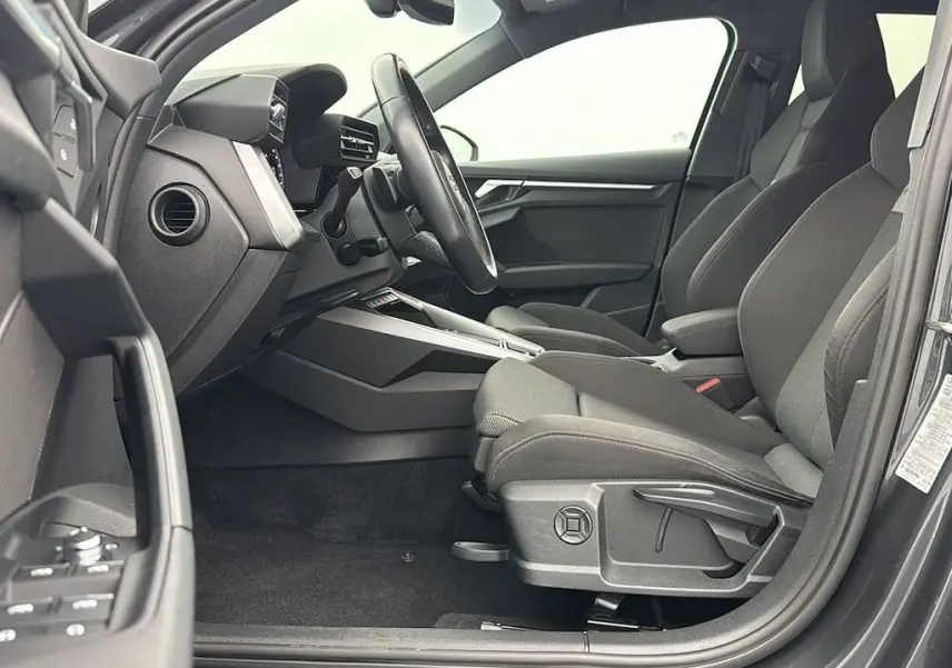 Vue intérieure côté conducteur de l'Audi A3 Sportback 2021 gris Manhattan, montrant sièges et tableau de bord modernes.