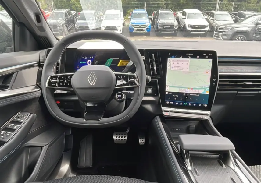 Vue intérieure avant du Renault Austral gris schiste, volant multifonctions et écran tactile central avec navigation visible.