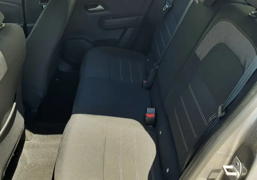Vue intérieure côté droit des sièges arrière en tissu gris foncé de la Dacia Sandero Stepway 2025, porte ouverte.
