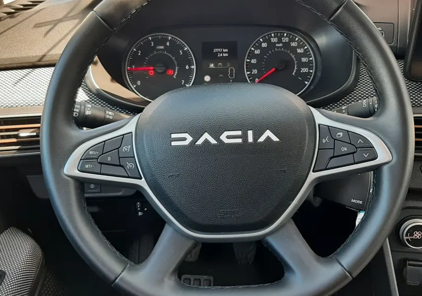 Vue rapprochée du volant noir de la Dacia Sandero Stepway 2025 avec commandes intégrées et tableau de bord visible.