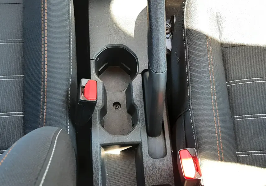Vue plongeante sur la console centrale grise entre les sièges tissu gris avec surpiqûres orange du Dacia Sandero Stepway 2025.