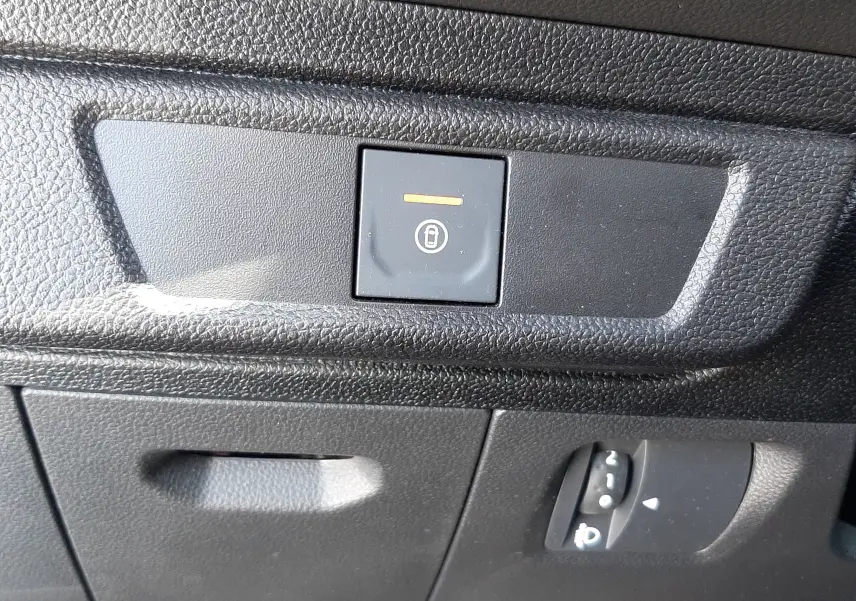 Gros plan sur le bouton de verrouillage centralisé et le réglage des phares dans l’habitacle gris foncé du Dacia Sandero Stepway.