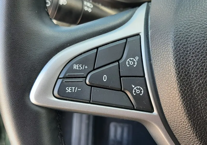 Gros plan sur les commandes de régulateur de vitesse au volant noir de la Dacia Sandero Stepway gris schiste 2025.